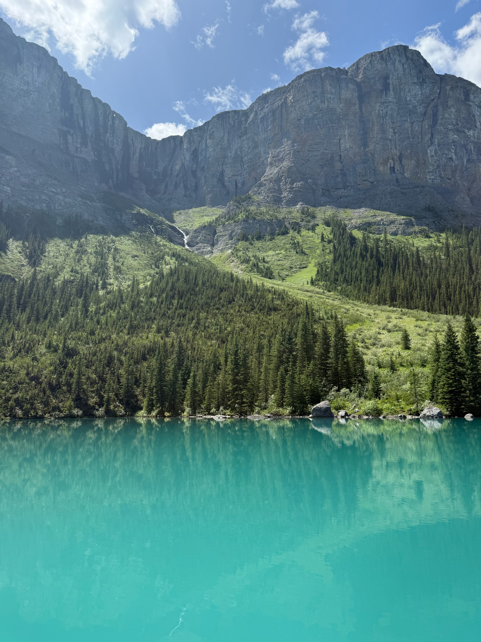 Turquoise glacial lake with massive cliff wall and waterfall, Jasper National Park