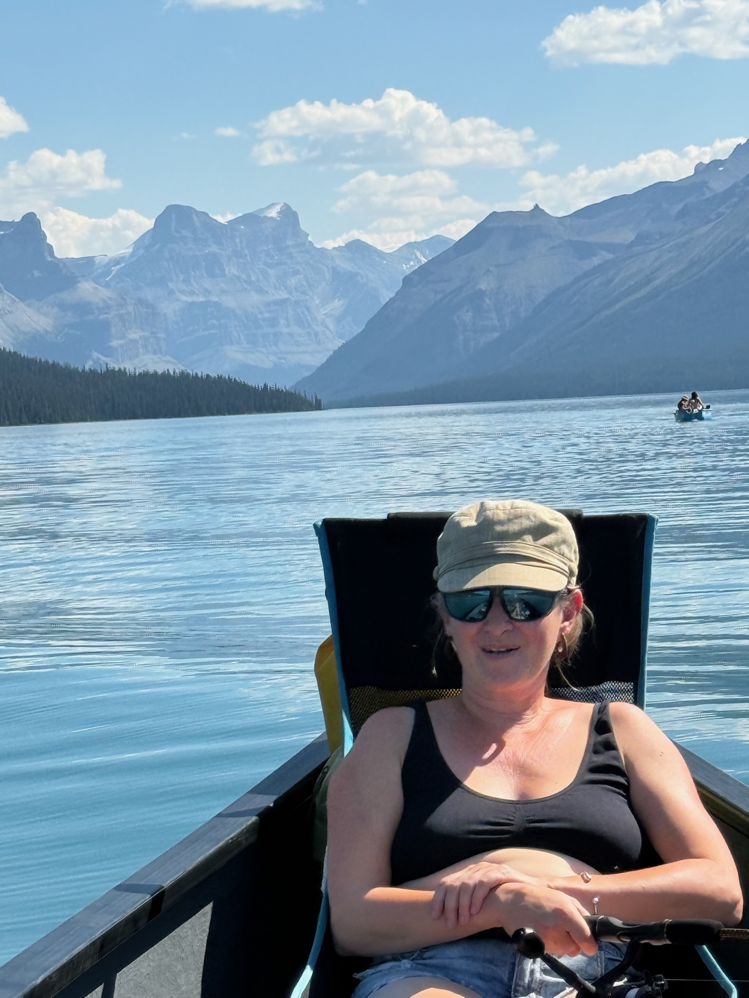 Guests relaxing on boat with Rocky Mountain backdrop, Jasper National Park