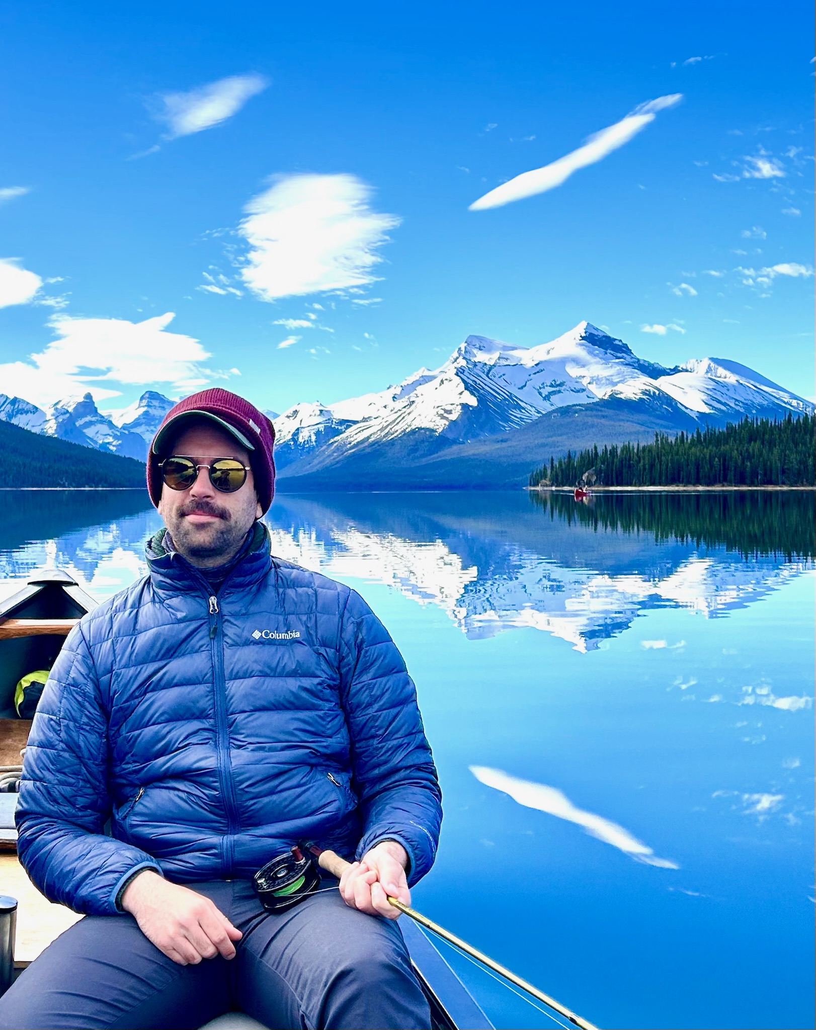 Fly fishing in canoe on mirror-calm Maligne Lake with Spirit Island, Jasper National Park
