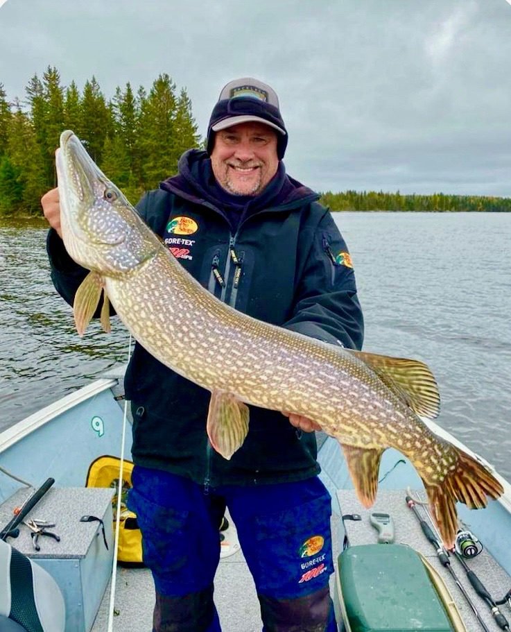 Man holding massive trophy Northern Pike with big smile, Talbot Lake Jasper National Park