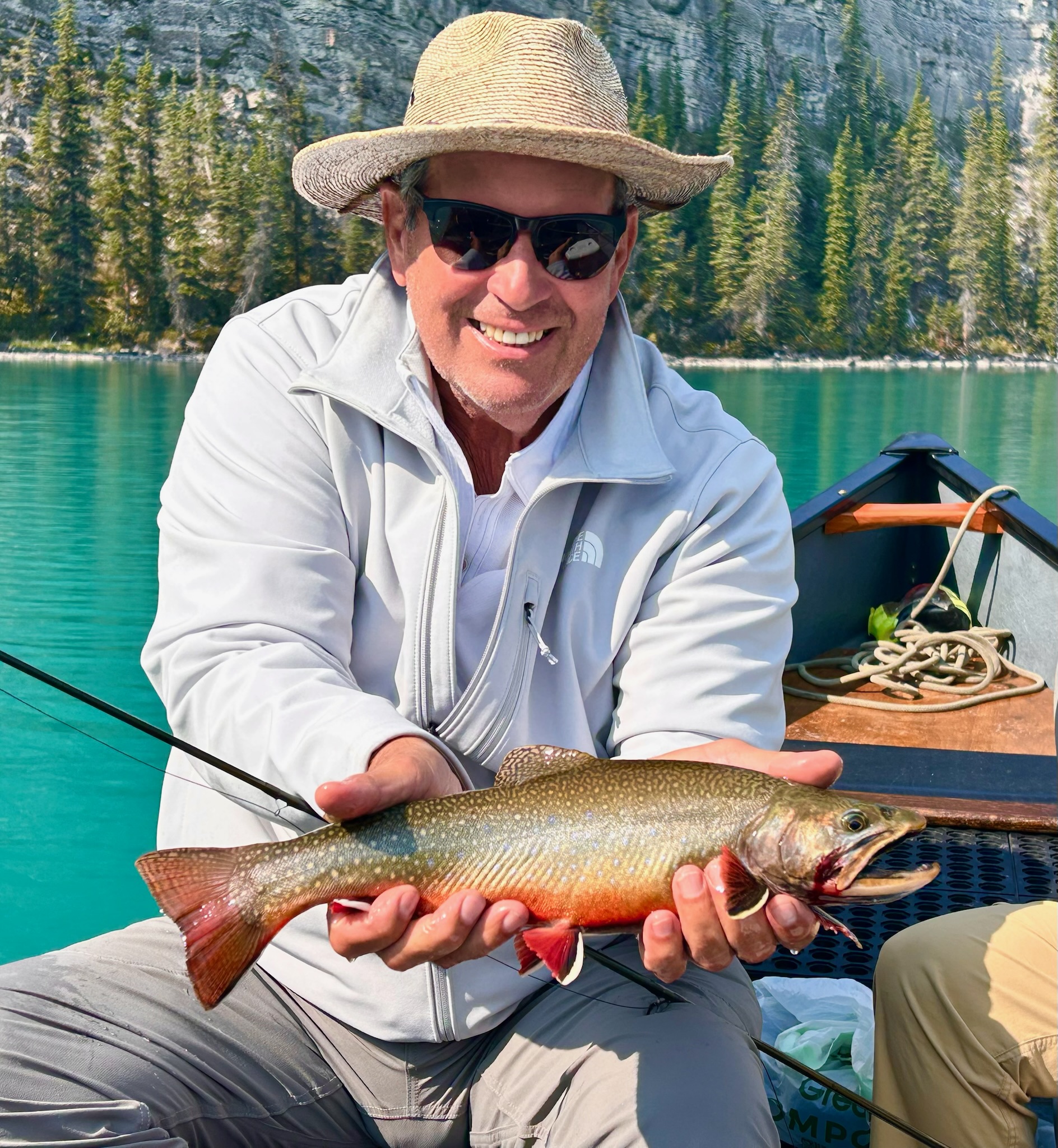 Man in boat holding large vivid orange spawning brook trout, Maligne Lake Jasper