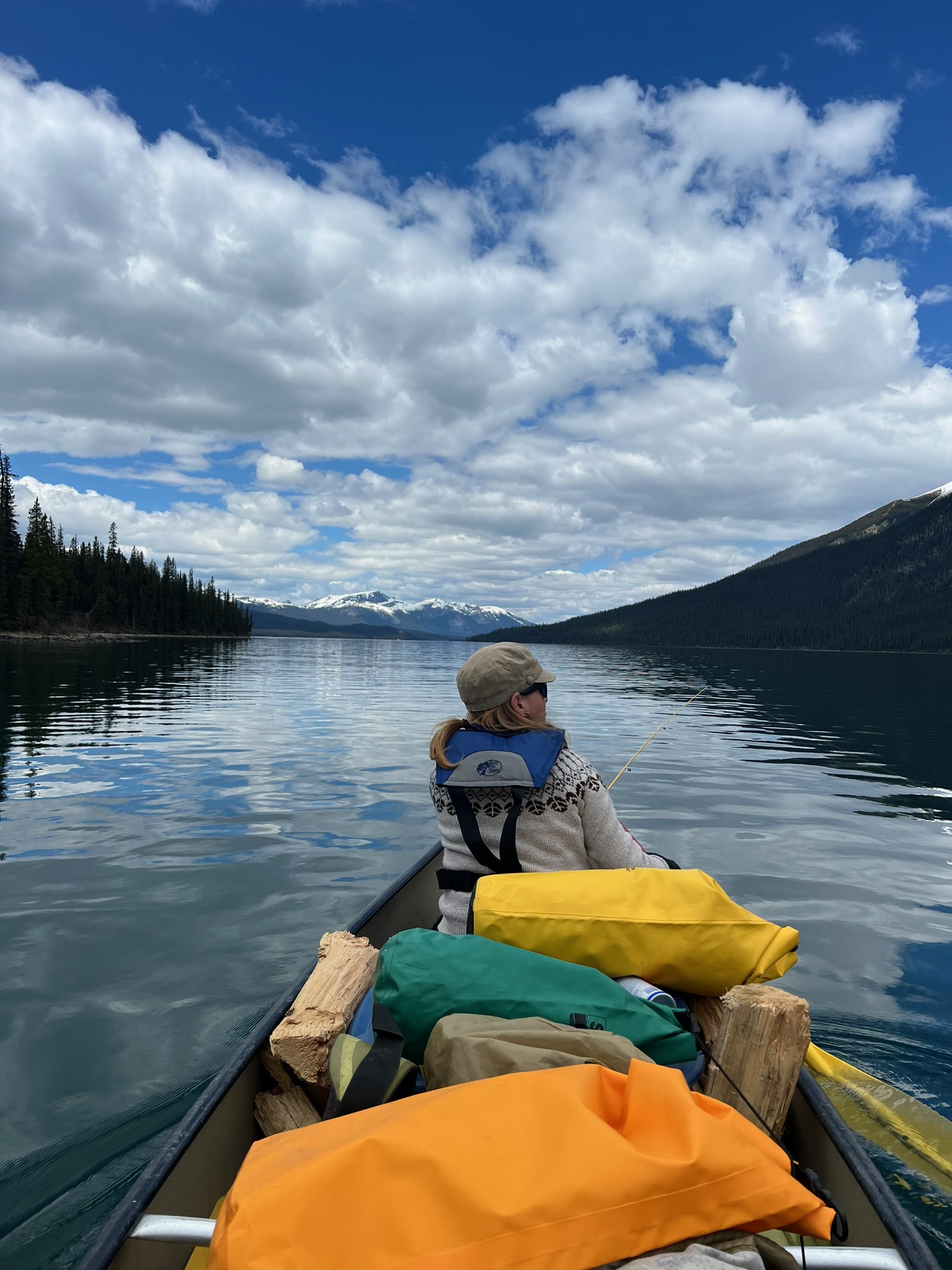Woman in canoe with fishing rod, snow-capped mountains, Maligne Lake Jasper