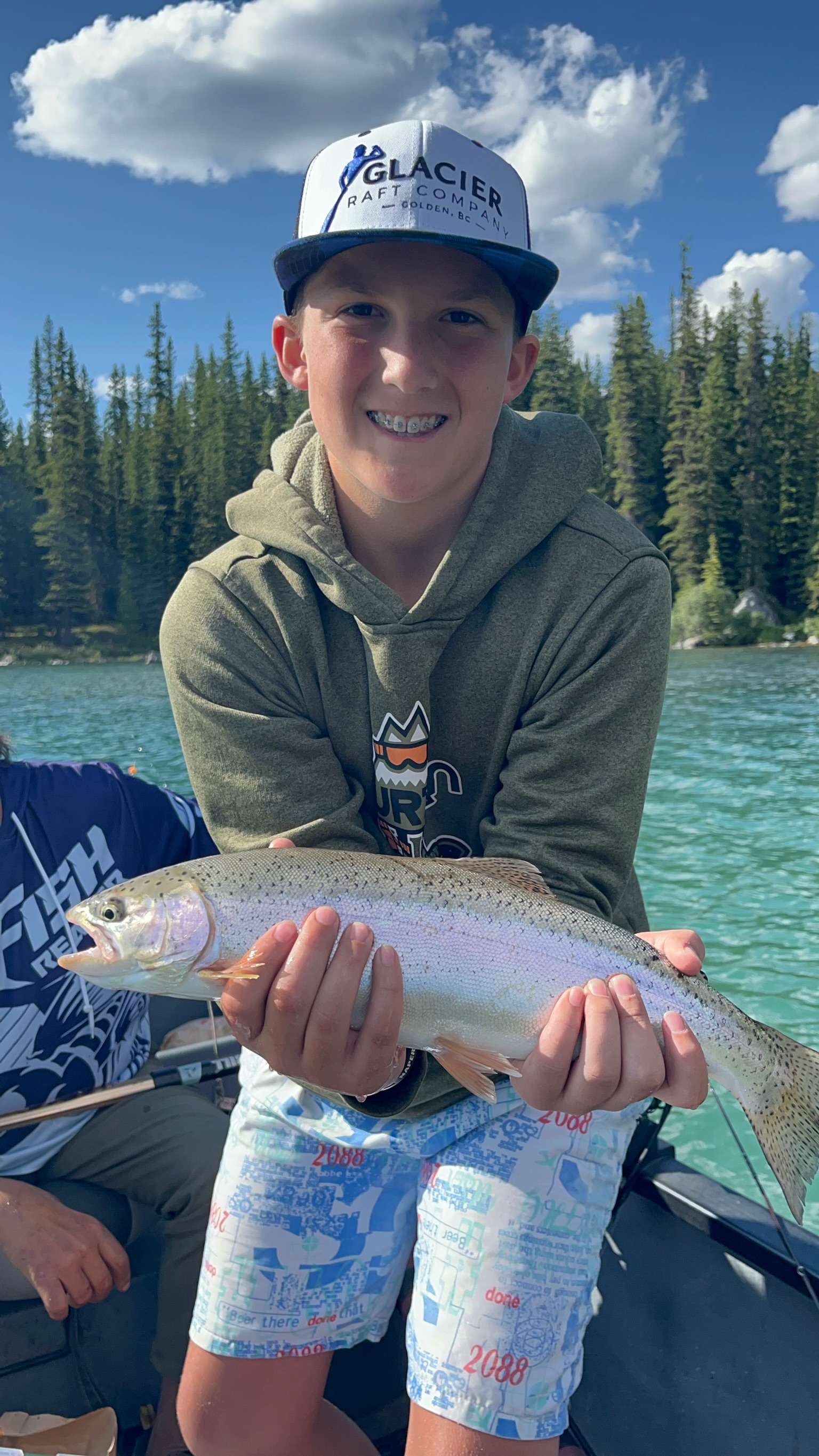 Young boy with huge smile holding rainbow trout, family guided fishing Jasper National Park