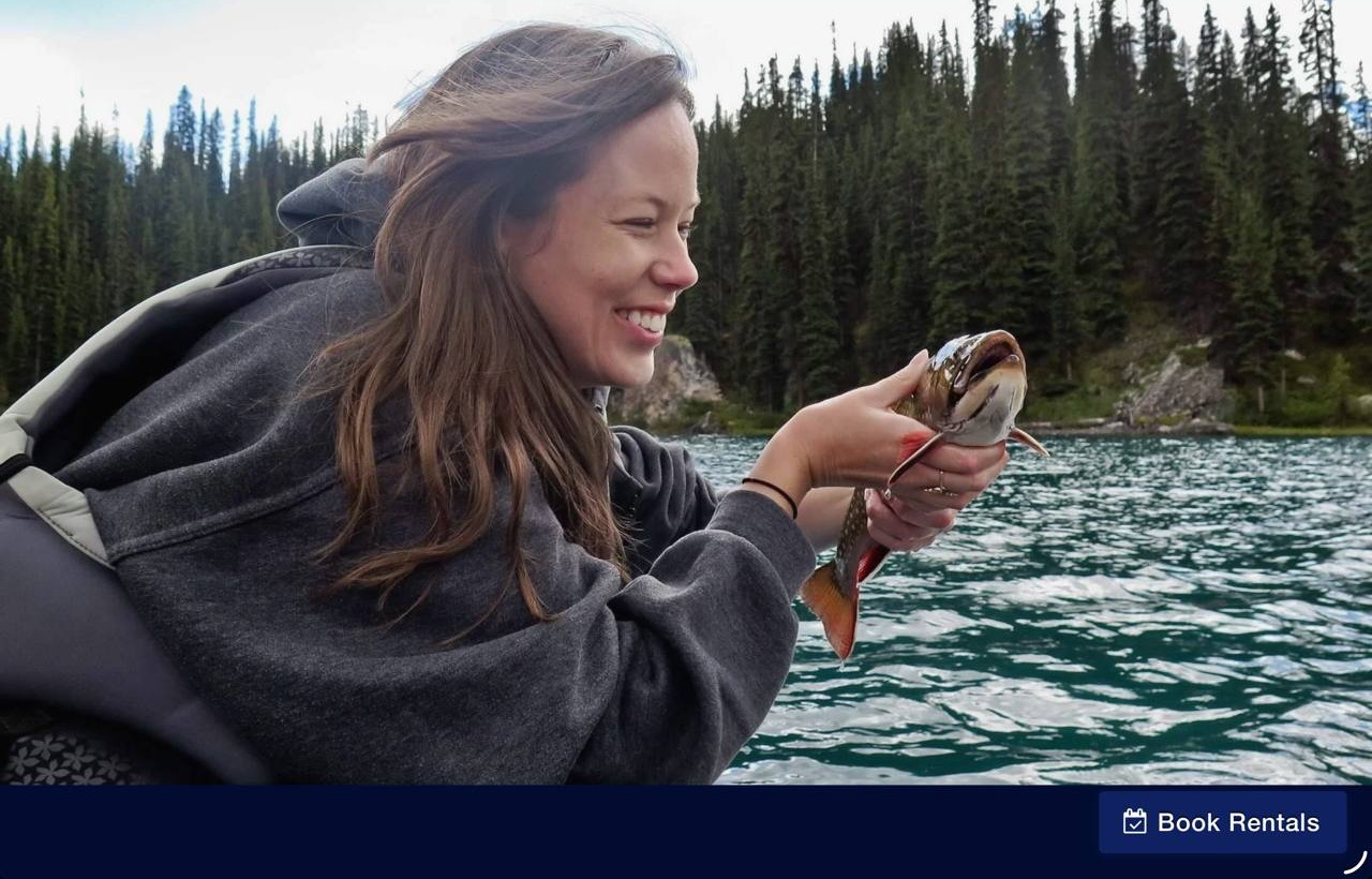 Woman laughing with delight while holding a brook trout on a guided fishing trip, Jasper National Park — no experience needed